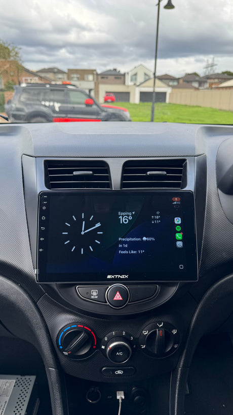 Carplay dashboard with digital display showing temperature and time, with a residential area in the background.